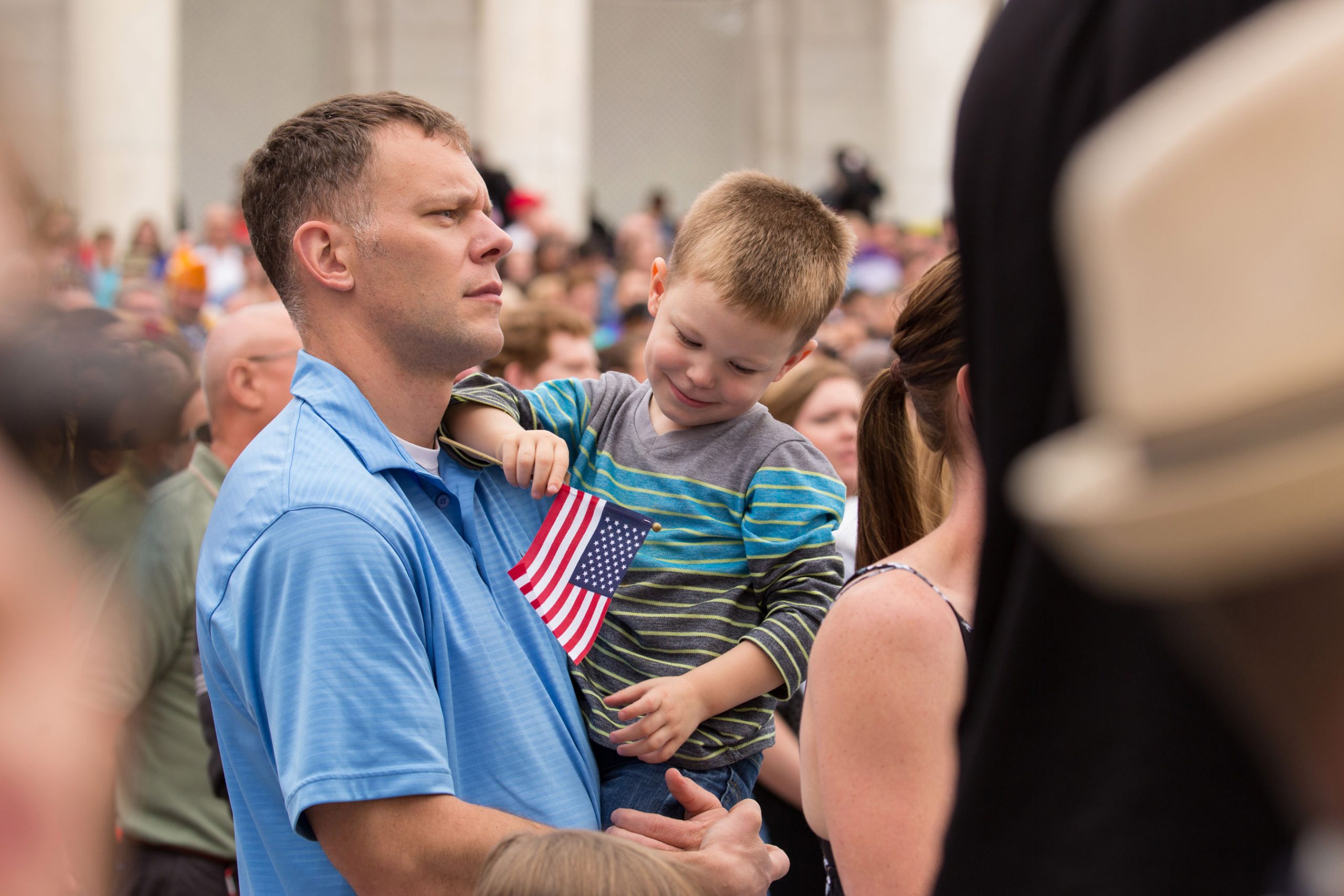 Veteran with a younf child carring a flag.